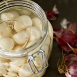 Peeled garlic in an airlock jar with a fermentation weight submerging the cloves