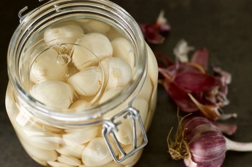 Peeled garlic in an airlock jar with a fermentation weight submerging the cloves